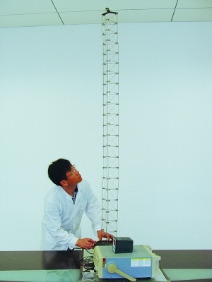 這是伸展開(kāi)的衛(wèi)星太陽(yáng)能電池用盤(pán)壓伸桿，20厘米長(zhǎng)螺旋狀的盤(pán)壓伸桿（右側(cè)小圖）打開(kāi)后能達(dá)2米長(zhǎng)（8月7日攝）。（新華社發(fā)）